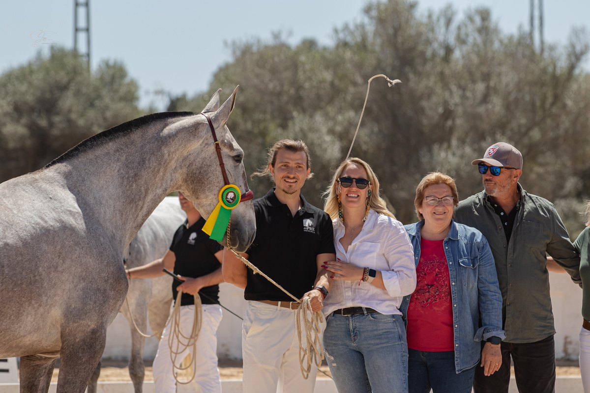 The Son Maig family with a grey mare wearing a rosette at a breeding show